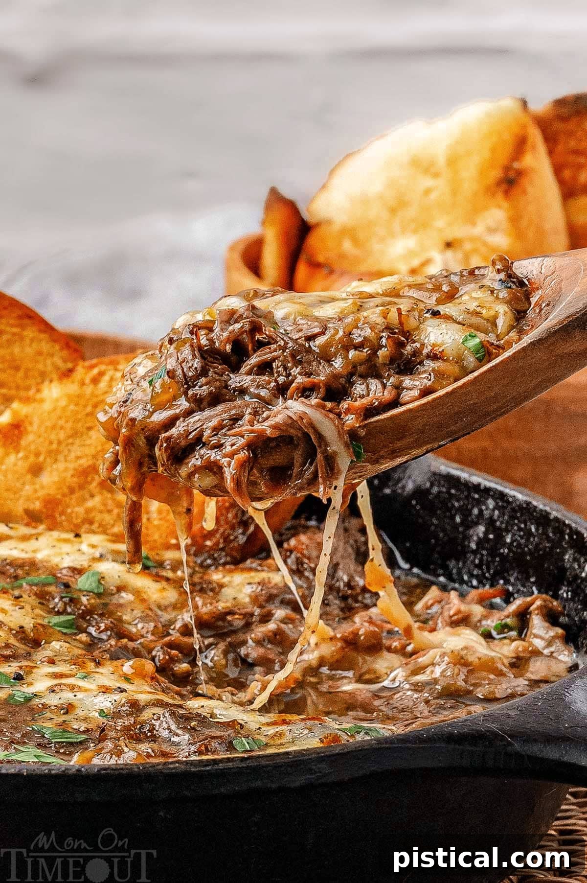 French onion soup pot roast being lifted out of the pan after the roast has been shredded, showcasing the tender beef and rich sauce.