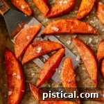Top down look at roasted sweet potato wedges on parchment lined baking sheet.