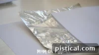 DIY Shiny Foil Snowflakes 4 Aluminum foil sandwiched between two sheets of white paper, ready for cutting into a square