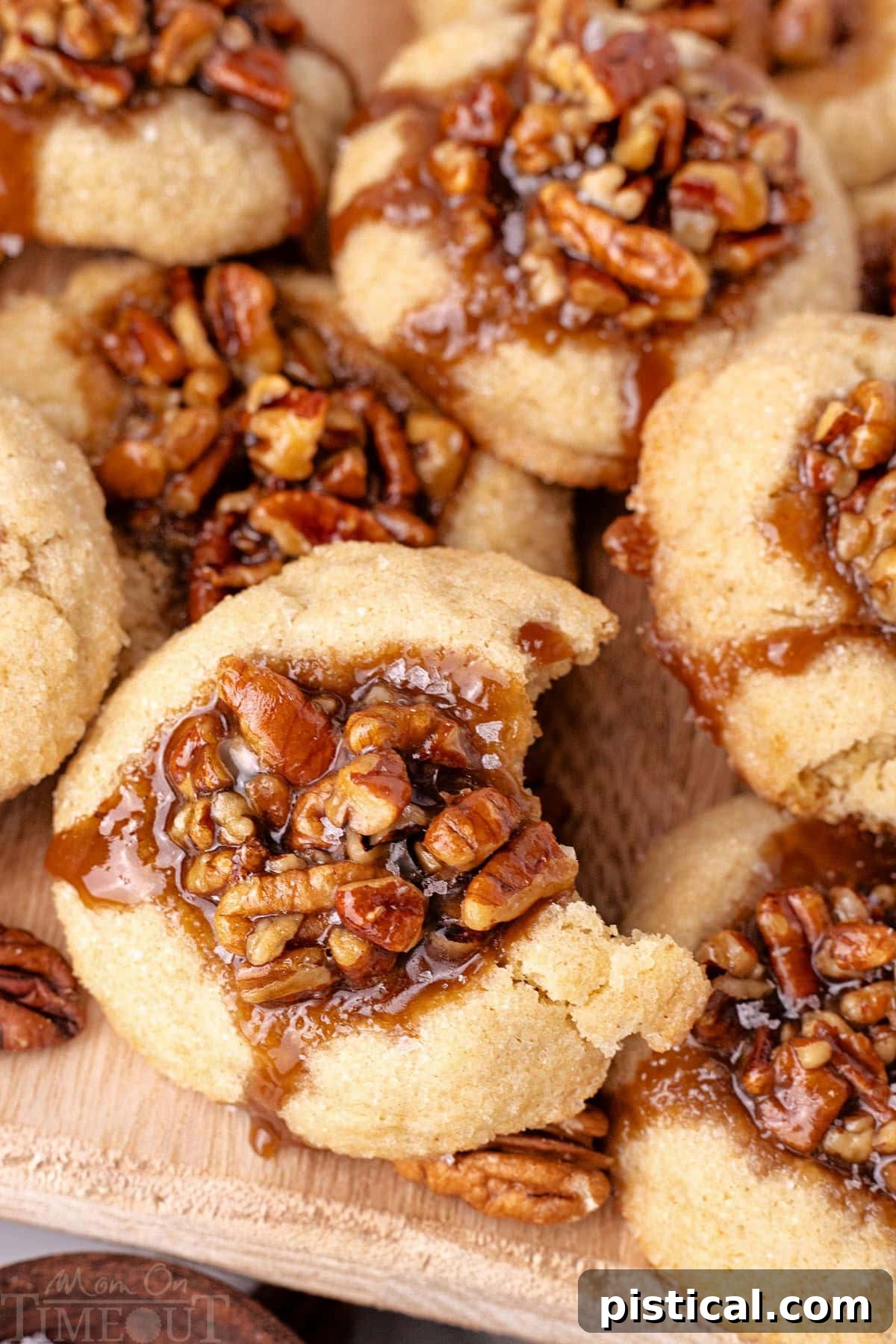 Shot of pecan pie cookies recipe piled on wood board. Top cookie has a bite taken out of it.