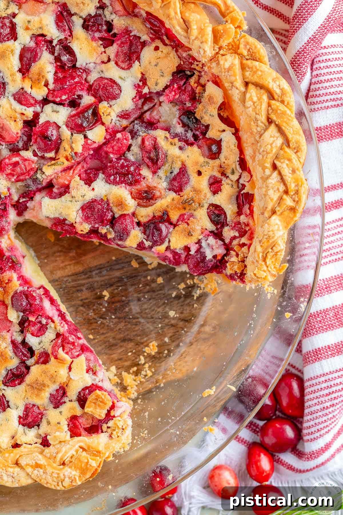 Ruby Red Custard Delight 3 An overhead view of a whole Cranberry Custard Pie in a glass pie plate, with one slice elegantly removed, showcasing the vibrant cranberry layer beneath the creamy custard, perfect for holiday gatherings.