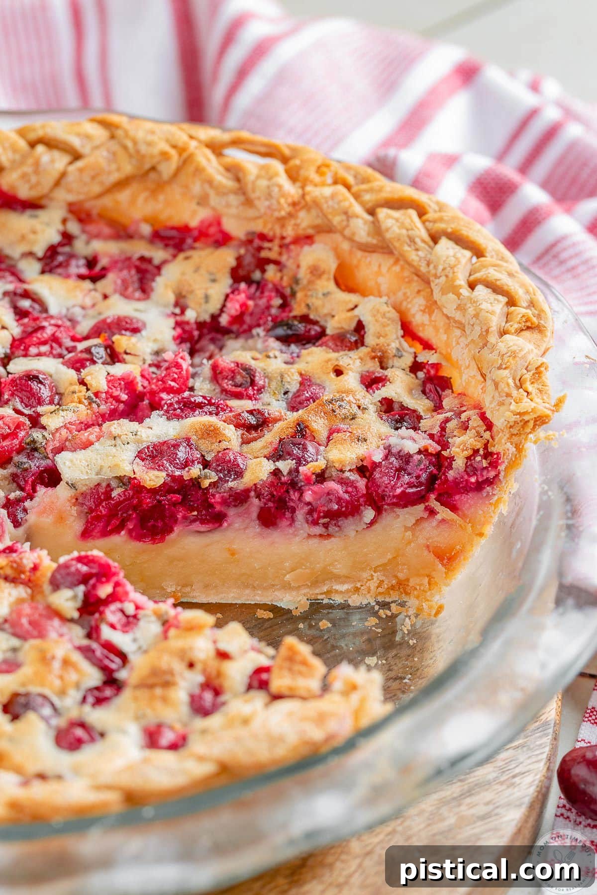 Ruby Red Custard Delight 7 An angled overhead shot of a baked Cranberry Custard Pie, showing the vibrant crimson cranberries nestled beneath the smooth, golden custard in a clear glass pie plate, ready to be served.