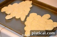 Crescent roll dough slices arranged on a baking sheet in the shape of a Christmas tree