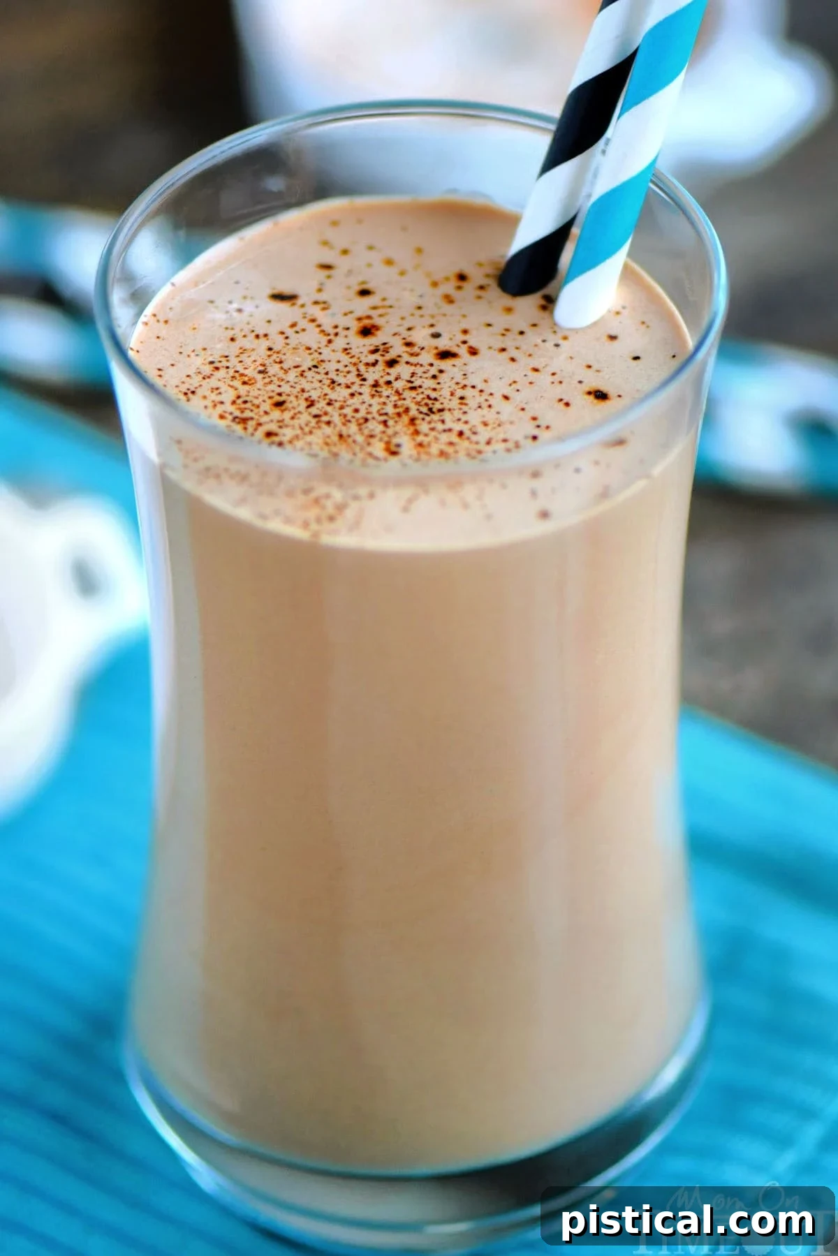 A close-up view of the coffee protein shake recipe, beautifully presented in a tall glass and ready to be enjoyed. The delicate sprinkle of espresso powder on top of the shake adds an elegant finish and hints at its rich flavor. An inviting and energizing beverage.