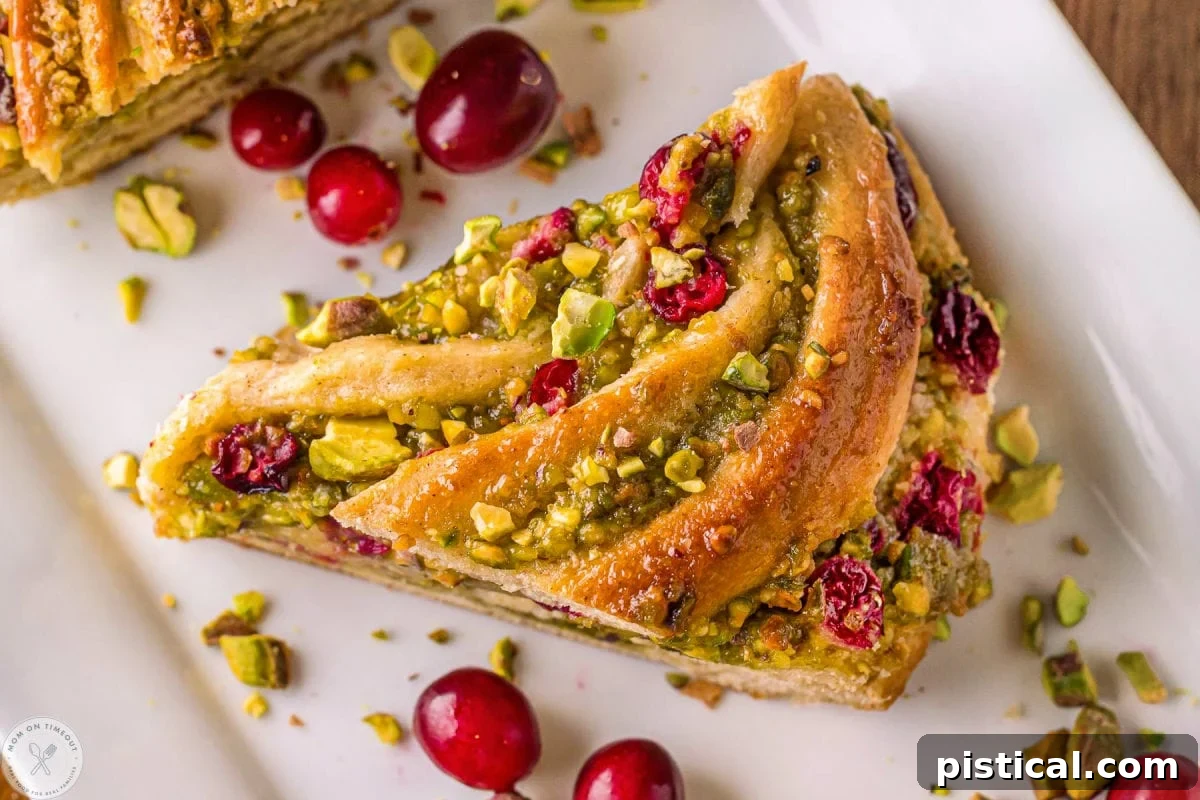 Festive Cranberry Pistachio Babka Crown 3 Wide shot of piece of babka bread on white tray. Shown with cranberries and pistachios.