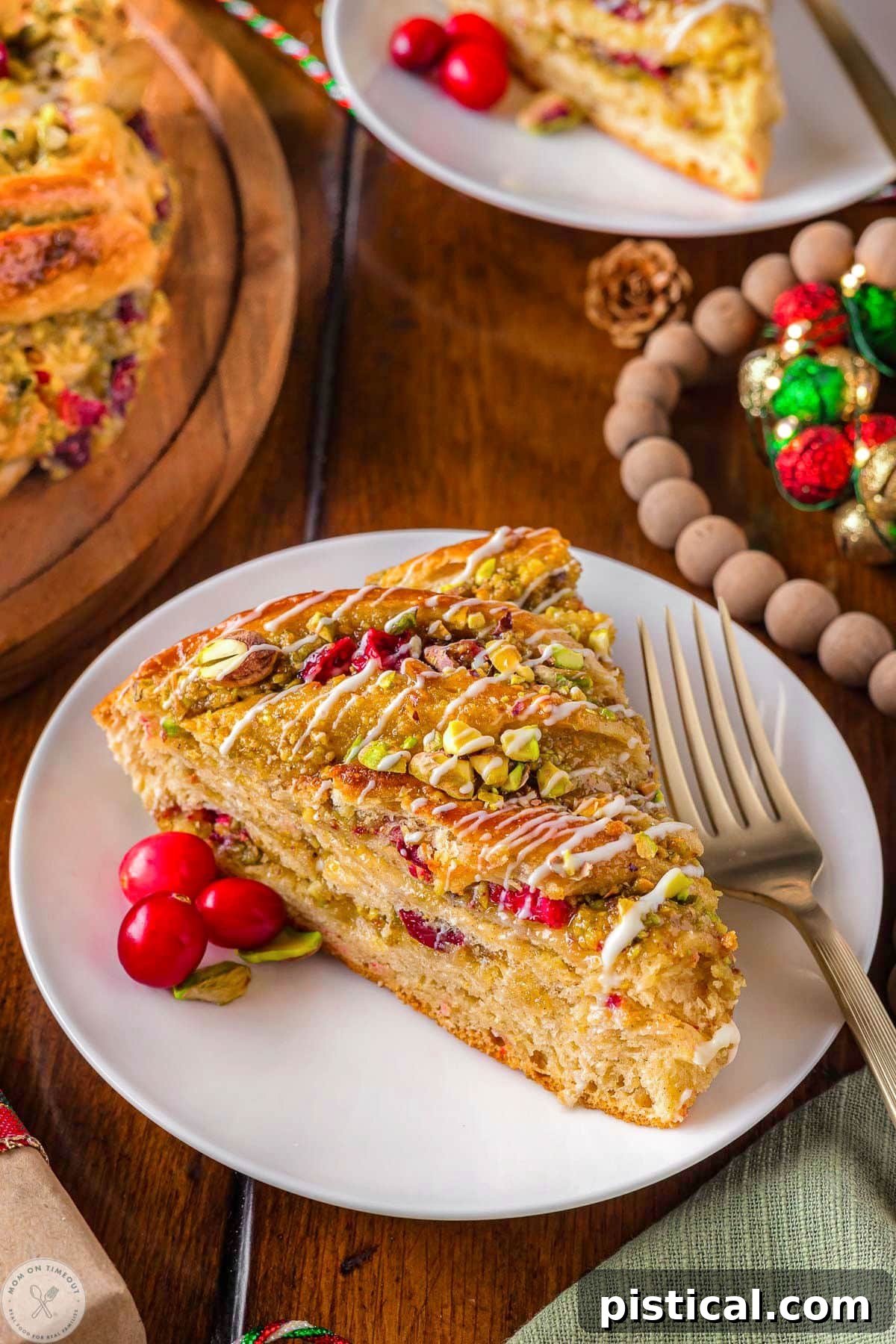 Festive Cranberry Pistachio Babka Crown 6 Piece of holiday babka bread on white round plate made with cranberries and pistachios.