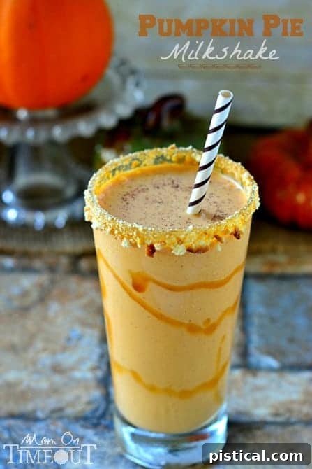 Close-up of a beautifully presented pumpkin pie milkshake with caramel rim, crushed cookies, and a dusting of spice.