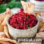 Large hand made pottery bowl with fresh cranberry salsa in it. The bowl is surround with cinnamon sugar chips.