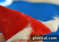 Whimsical Santa Mouse Ornament 9 Small cotton pom-pom being glued to the tip of the Santa hat