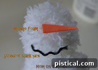 Close-up of the three finished pom poms in different sizes, ready for snowman assembly