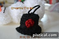 Pom pom snowman wearing a small crocheted black hat