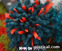Three pom poms of varying sizes and colors, ready for use in craft projects.
