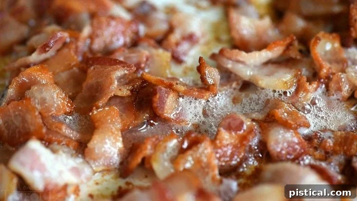 Bacon sizzling in a pan, a key step for this green bean recipe