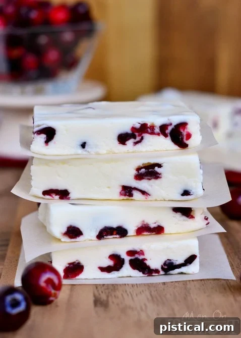 Close-up of a square of white chocolate cranberry fudge, showcasing its creamy texture and visible cranberries.