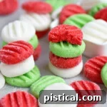 Red, white, and green Christmas peppermint patties stacked and scattered on parchment paper, ready for display.