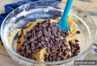 chocolate chips added to chocolate chip cookie dough in glass bowl