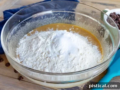 adding dry ingredients to wet ingredients in glass bowl