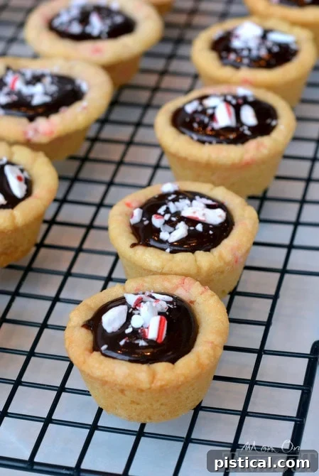 Dark Chocolate Peppermint Sugar Cookie Cups filled with chocolate ganache and topped with Candy Cane Hershey's Kisses. | MomOnTimeout.com #christmas #recipe Freshly baked Dark Chocolate Peppermint Sugar Cookie Cups cooling on a rack, showing the perfect golden edges and deep cookie wells.