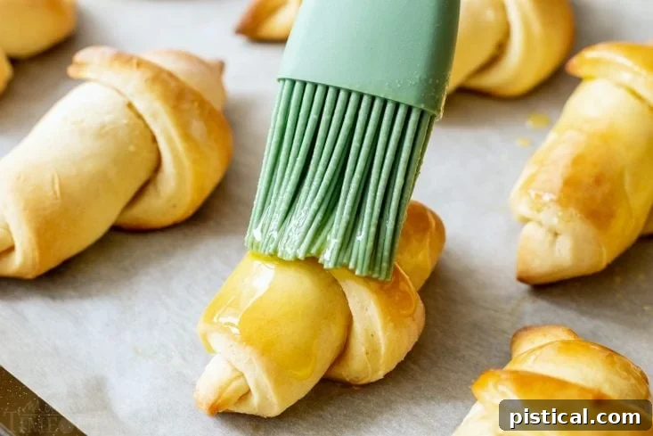 Pillowy Soft Homemade Crescent Rolls 8 Homemade crescent rolls being brushed with melted butter for a perfect finish