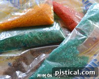 Adding food coloring to sugar in a plastic bag, showing the initial mixing process.