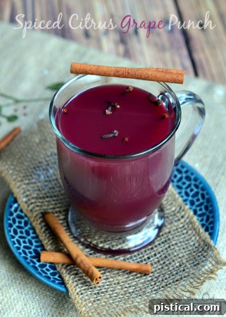 A slow cooker filled with warm spiced citrus grape punch, garnished with orange slices.