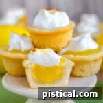 A stack of lemon meringue cookie cups on a white cake stand.