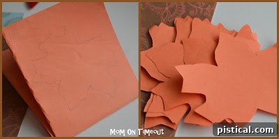 Cutting out fall-colored paper leaves using a template for a Thanksgiving gratitude tree.