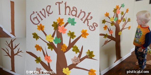 Adding 'Give Thanks' banner and artificial leaves to complete the Thanksgiving gratitude tree decoration.