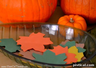 Close-up of a child writing a thankful message on a fall-colored leaf for the gratitude tree.