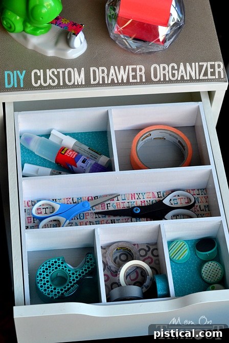 A fully organized desk drawer with a colorful DIY organizer filled with various office supplies like pens, clips, and tape.