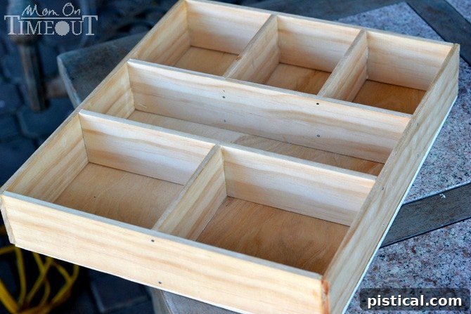 Pencil lines traced on a plywood base, outlining the compartments for a DIY drawer organizer.