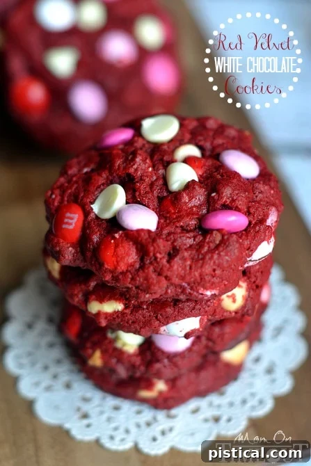 Three perfectly baked Red Velvet White Chocolate Cookies with M&Ms, stacked together on a white plate, highlighting their festive appearance.