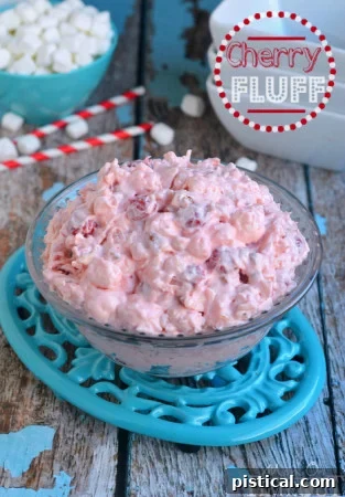 A bowl of creamy Cherry Fluff dessert salad, garnished with cherries, a sweet and simple treat.