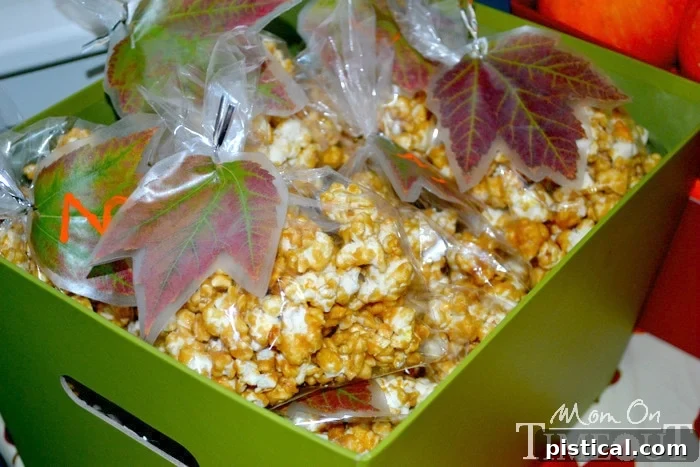 Basket filled with individual goodie bags of caramel corn, each decorated with a handmade leaf tag