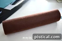 Smoothly wrapping the felt around the cardboard roll, ensuring full coverage and a tidy appearance for the pumpkin base.
