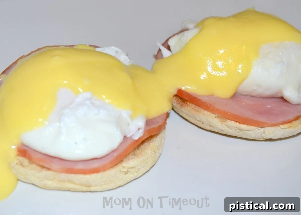 Classic Eggs Benedict with perfectly poached eggs, Canadian bacon, and rich hollandaise sauce on a toasted English muffin, garnished with fresh chives, served on a white plate.