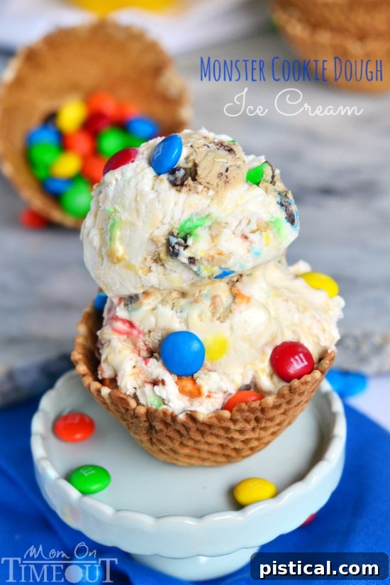 A large, tempting scoop of Monster Cookie Dough Ice Cream served in an adorable waffle cup, generously topped with extra M&Ms and ready to be enjoyed.