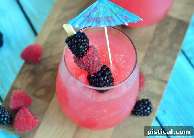 Close-up of a refreshing Raspberry Acai Slush cocktail, garnished with fresh berries and an umbrella.