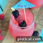 Close up of a Raspberry Acai Slush in a glass, garnished with berries.