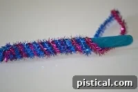 Close-up of pipe cleaners being wrapped around a popsicle stick to form the butterfly body