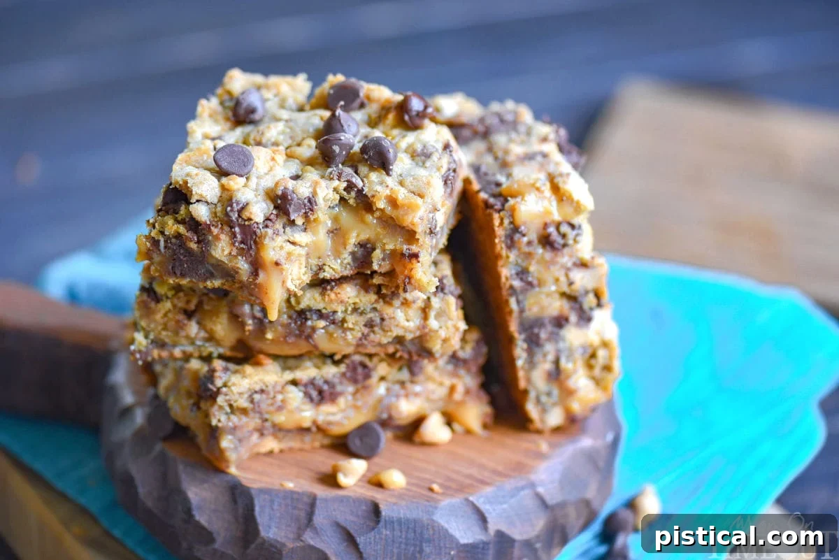 Three golden-brown peanut butter caramel toffee chocolate chip cookie bars, showcasing their generous layers of cookie, caramel, and toppings, stacked appealingly on a wooden surface.