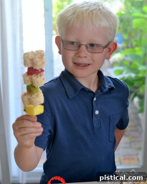 Smiling child holding a Funfetti Rice Krispies Treats Fruit Kabob