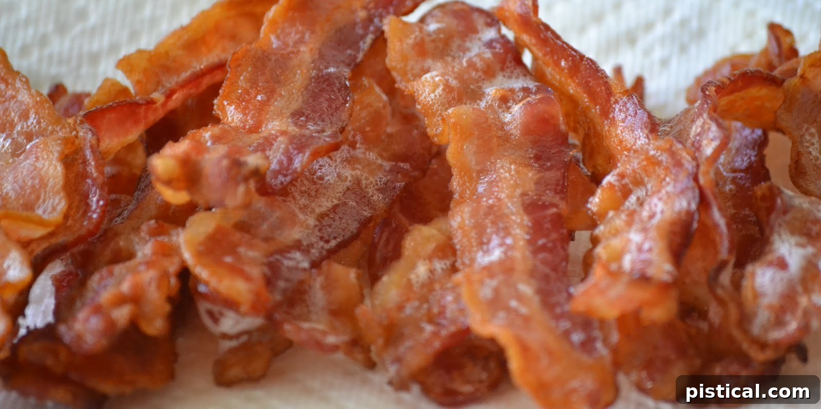 Crispy, golden-brown bacon strips fresh out of the oven, draining on paper towels.