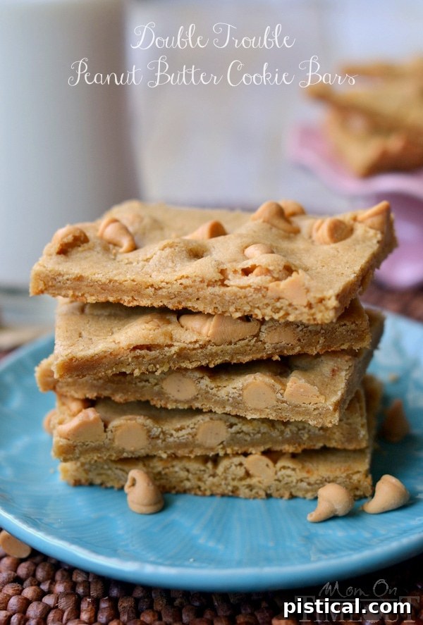 Hand holding a piece of Double Trouble Peanut Butter Cookie Bar cut into a triangle.