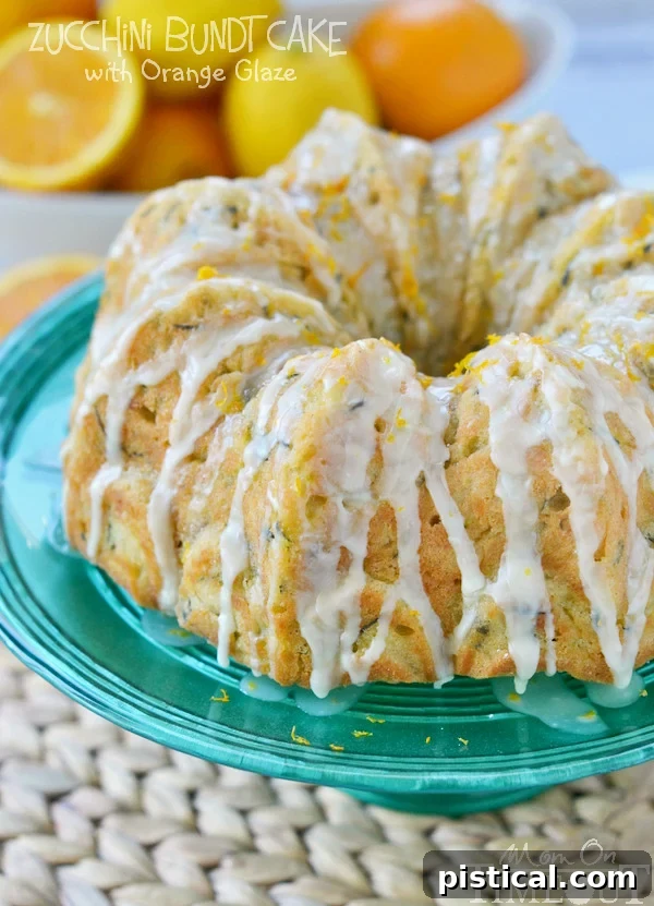 Velvet Zucchini Bundt 2 A beautifully baked Zucchini Bundt Cake, generously coated with a glistening orange glaze, ready to be served. It sits elegantly on a stand, promising a delightful treat.