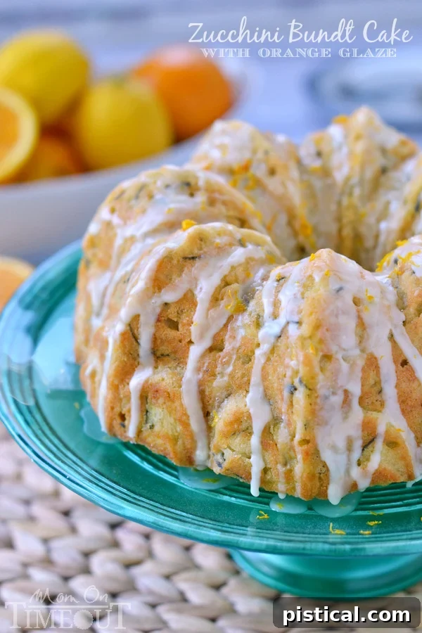 Velvet Zucchini Bundt 6 A whole Zucchini Bundt Cake with a generous drizzle of orange glaze, presented on a vibrant green cake stand, ready to be enjoyed.