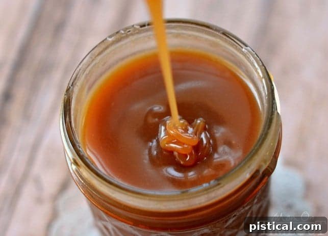 Velvet Bourbon Buttermilk Caramel 4 Buttermilk Bourbon Caramel Sauce being spooned from a jar, highlighting its pourable consistency. MomOnTimeout.com