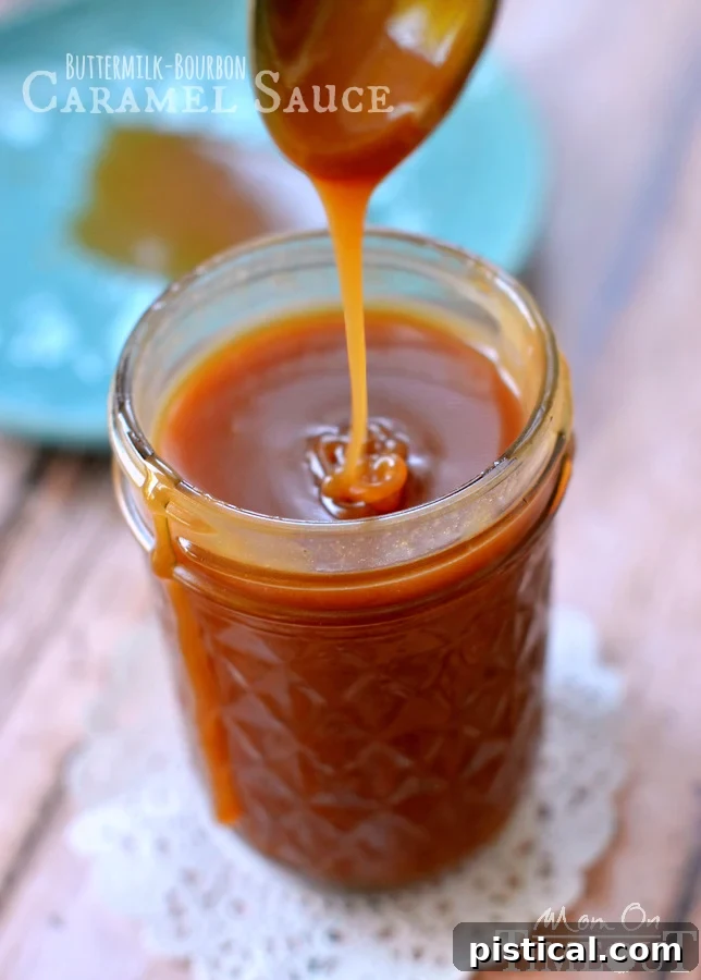Velvet Bourbon Buttermilk Caramel 5 A hand dipping a spoon into a jar of delicious Buttermilk Bourbon Caramel Sauce, perfect for tasting. MomOnTimeout.com