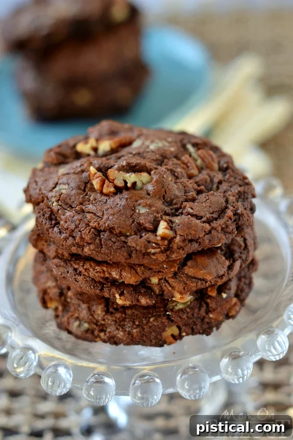 Ultimate Chocolate Toffee Pecan Cookies 5 A hand reaching for a warm, freshly baked Giant Chocolate Toffee Pecan Cookie, emphasizing its rich texture and tempting ingredients.