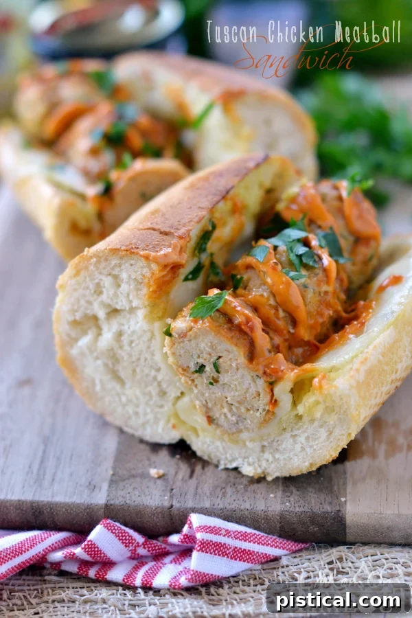 Close-up of a Tuscan Chicken Meatball Sandwich showcasing the golden meatballs and melted cheese.